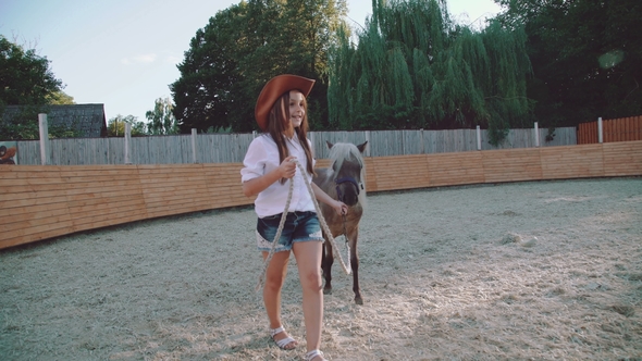 Pretty Girl Walks with a Beautiful Pony on the Arena