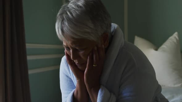 Depressed senior mixed race woman at home with head in hands