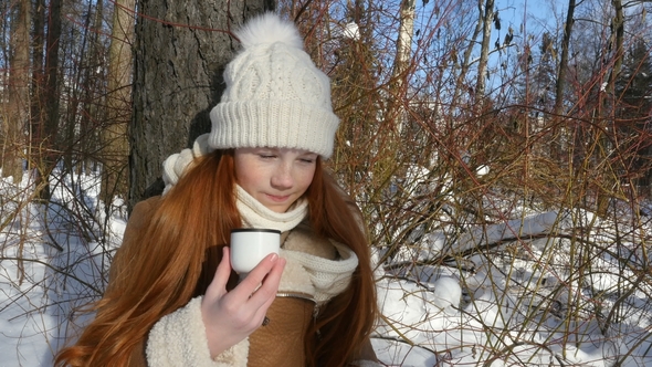 Red-Haired Girl Teenage Eating a Bread and Drinks a Tea on Winter Sunny Day