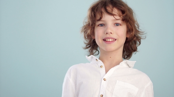 White Shirt on the Teenager. Beautiful Caucasian Smiling Child, on a Light Blue Background