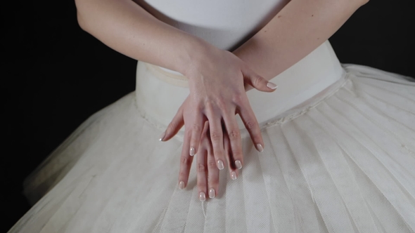 Unrecognizable Ballerina in White Tutu Dress. Black Background. The Dancer Stands and Slowly Moving