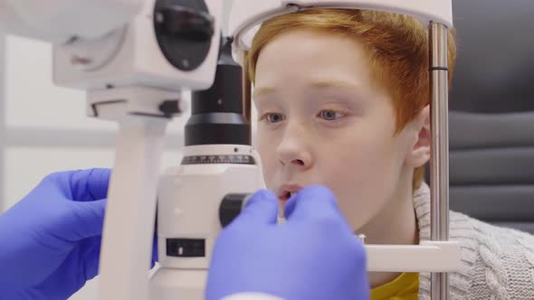 Redhead Boy Getting Slit Lamp Eye Exam in Ophthalmology Clinic