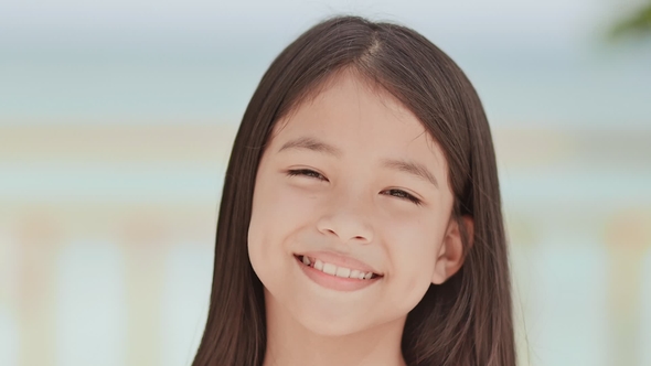 A Charming Philippine Schoolgirl Positively Poses. Face  on a White-blue Background of a Tropica