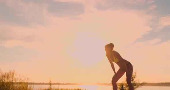 Athletic Girl Playing Beach Volleyball Jumps in the Air and Strikes the Ball Over the Net on a