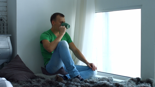 Man Drinking Coffee and Admires View From Window