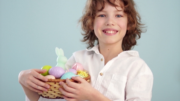 Happy Easter. A Schoolboy with an Easter Basket Smiling Cheerfully. Portrait on a Blue Background