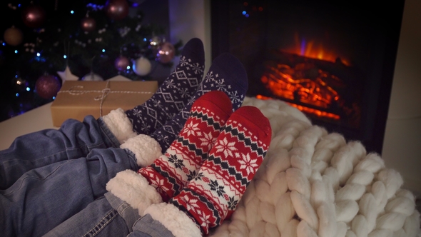 Couple Sitting in Woolen Socks near Fireplace on Christmas Holidays