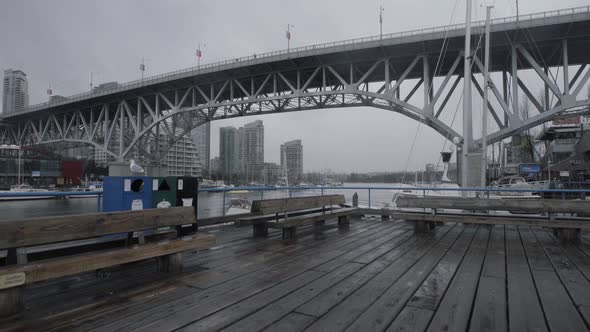 Wide shot of Granville island boardwalk and bridge on cloudy day