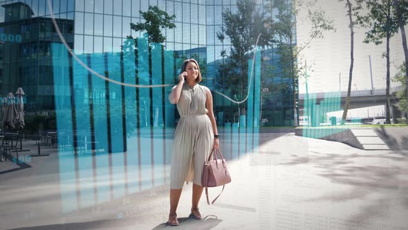 Young business woman is standing between office skyscrapers on the phone surrounded by digitally sup