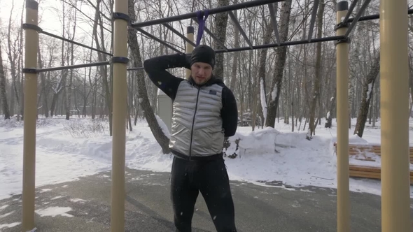Athlete Man Doing Squat Exercise with Sport Expander on Winter Sports Ground