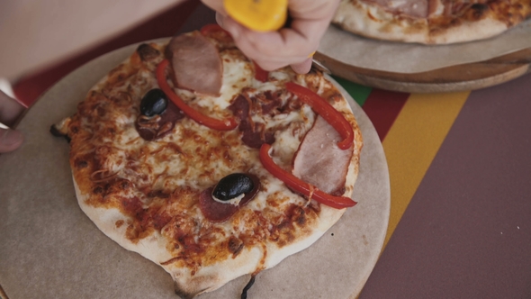 Person Slicing a Tasty Pizza into Slices with a Pizza Cutter