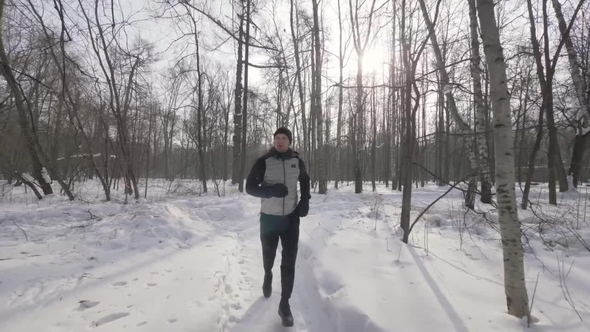 Portrait Athlete Man Running in Winter Forest . Winter Jogging in City Park
