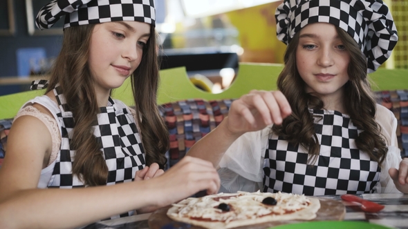 Two Cheerful Girls in Uniform Cooking a Pizza on Master Class in Cafe
