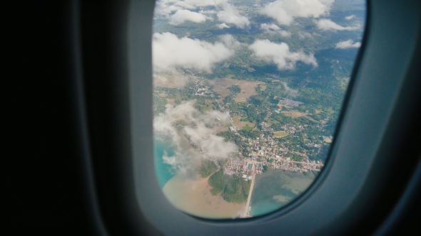 View Through an Airplane Window on the Tropical Island, Ocean, Sea, Sky and Clouds