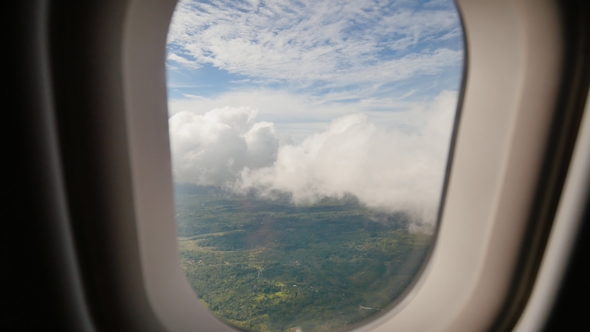 View Through an Airplane Window on the Tropical Island, Ocean, Sea, Sky and Clouds