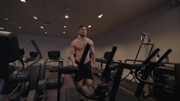 Muscular Man Doing Cardio Training on Treadmill in Healthy Club