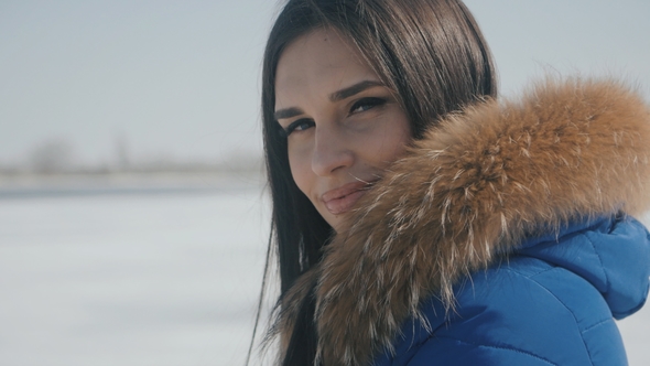 Portrait of Young Beautiful Brunette Woman in Winter on a Snow Background