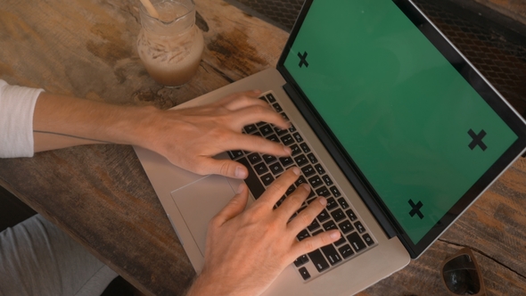 of Male Hands Working on a Laptop with Green Screen in Cafe