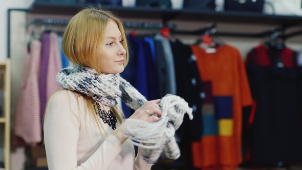 Attractive Woman Trying on a Model Looks Warm Scarf in a Clothing Store. Joyful Shopping