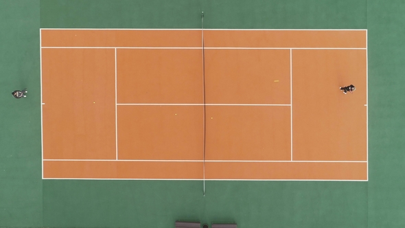 Players Are Playing Tennis on Green and Orange Court. Aerial Vertical Top Shot. Drone Is Hovering