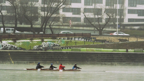 Rowing Four Moving Backwards on the River at Urban Area