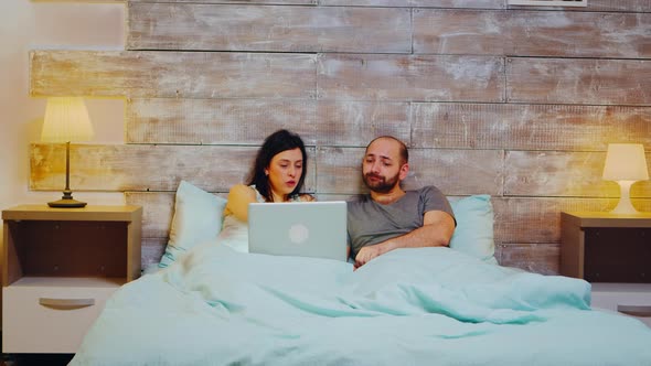 Young Couple in Pajamas Doing Shopping on Laptop