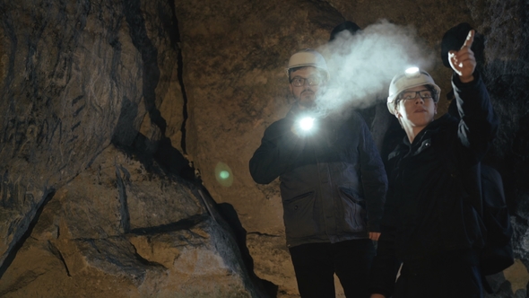 Two Speleologists Exploring the Cave in Darkness