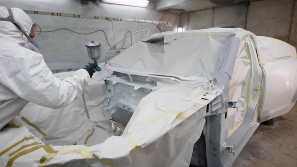 Woman Painter Is Spraying White Automobile Dye on a Details of Car Body, Wearing Protective Mask on alt