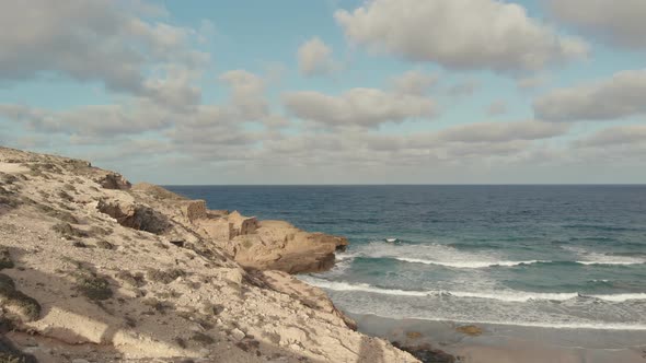 Cloudscape of Porto Santo beachfront with turquoise waves on white limestone.
