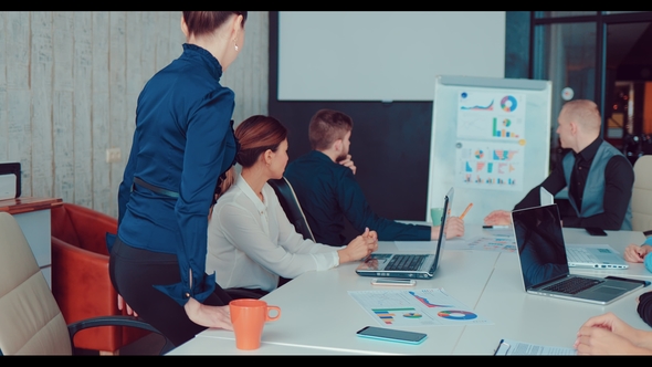 Director at a Meeting at the Office Points To a Woman Colleague To Give Her a Presentation