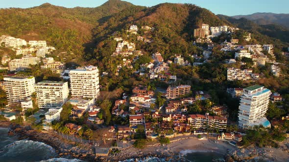 Hotels on mountain coastline in Playa Amapas, Puerto Vallarta Mexico at sunset, aerial