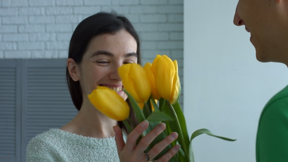 Lovely Woman Enjoying Smell of Flowers Given By Man