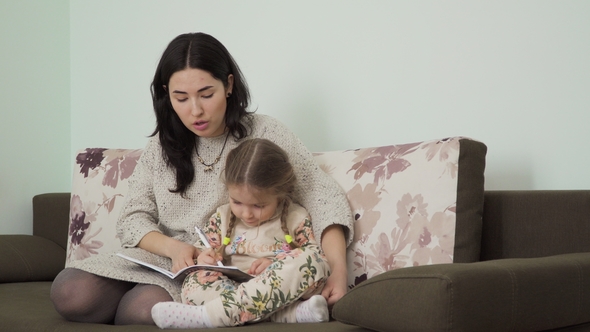 Young Woman Helps Her Daughter To Make Homework