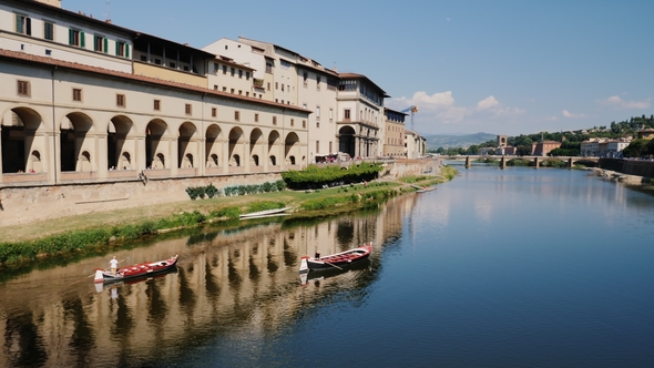 Two Boats Sail Along the Arno River, Beautifully Reflected in the Water. With a View of Florence and