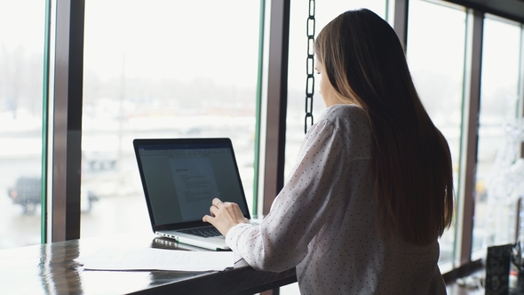 Young Beautiful Business Woman in White Shirt Working on Desk with Laptop and Document in Cafe.