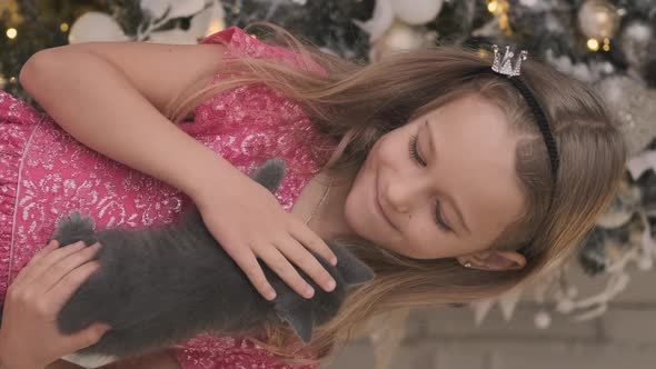 Happy Little Girl Holds Kitten By Xmas Tree