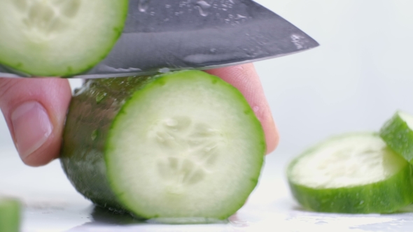 Cutting Raw Green Cucumber on a White Background.