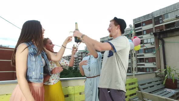 Hipster man toasting and drinking champagne with beautiful female friends