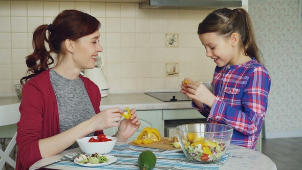 Happy Family of Young Mother and Cute Daughter Have Fun Grimacing Silly with Vegetables While