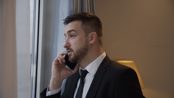 Confident Businessman Having Phone Call in Hotel