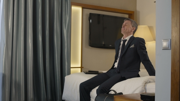 Exhausted Businessman Falling on Bed in Hotel