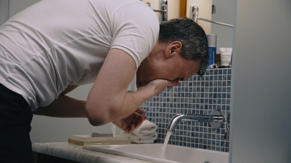 Crop Man Washing Face in Sink