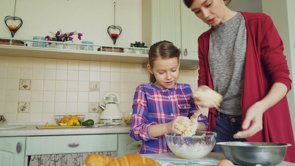 Happy Mother and Cute Daughter Cooking Together and Having Fun Stirring Dough in Hands. Family, Food