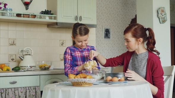 Cute Girl Helping Her Mother in the Kitchen Stirring Dough for Cookies Into Bowl. Mom Have Fun