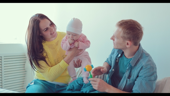 Mom Holds the Baby in Her Arms while Father Plays with Her