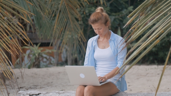 Woman Freelancer Works on the Beach