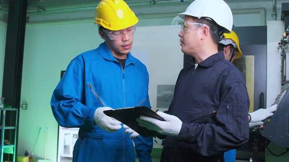 Professional engineering walking discuss inspecting with engineer team machinery factory area.