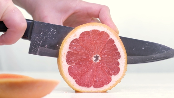 Grapefruit Fillets and Half of a Red Grapefruit on a Marble Chopping Board and White Background