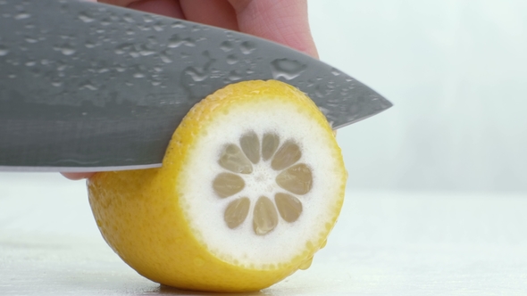 Knife a Cutting Juicy Lemon on a White Background.