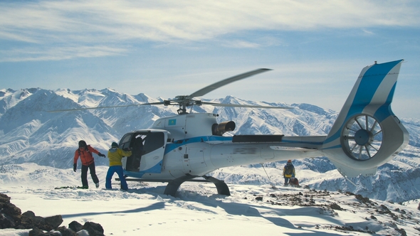 Skiers Unload Skis From a Landed Helicopter in the Winter Mountains